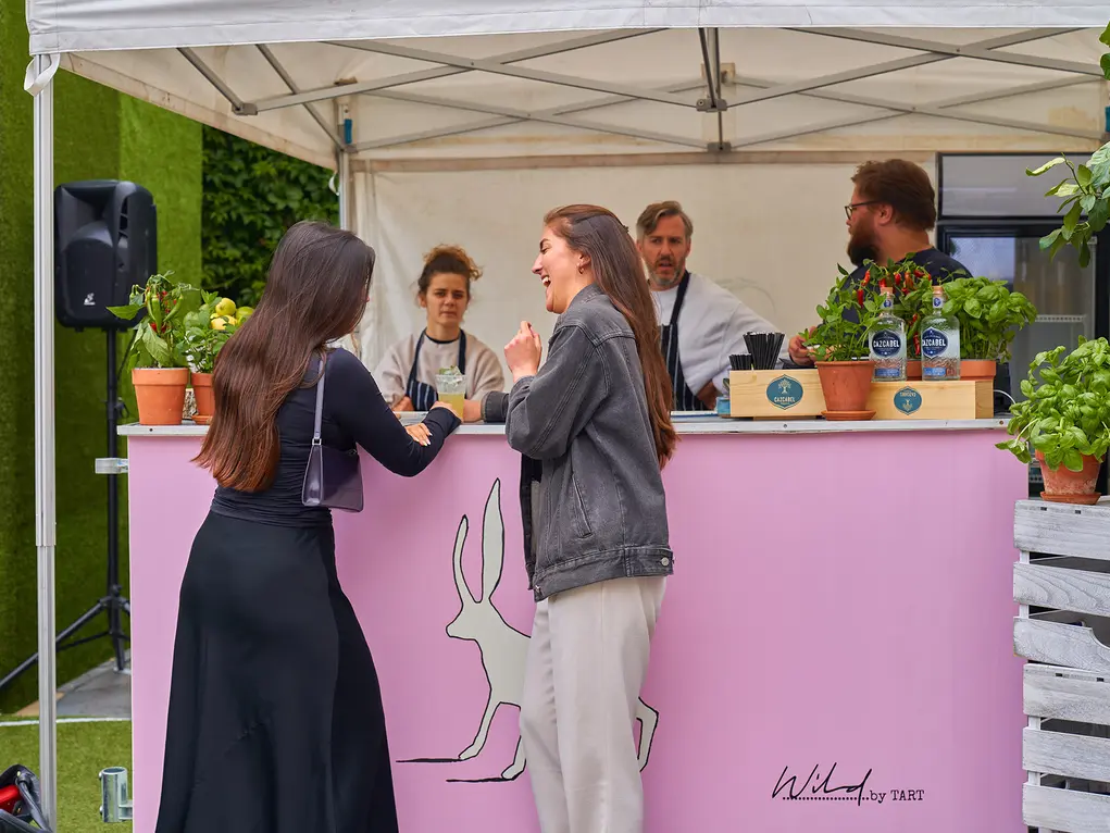 A pink bar with two women buying drinks